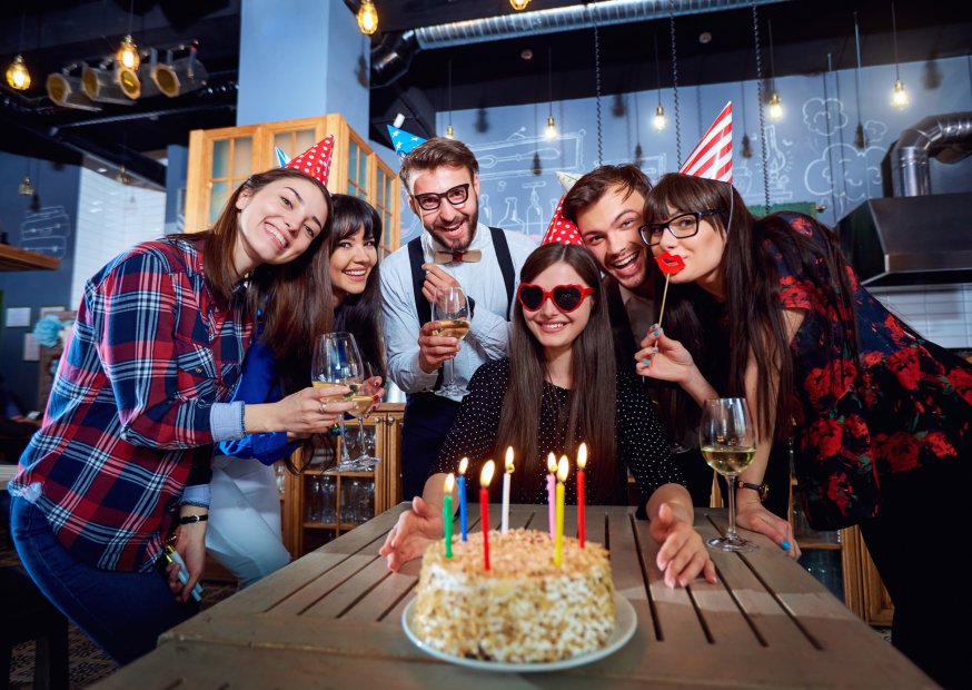 a (5) A group of friends gathers around a birthday cake, smiling and celebrating